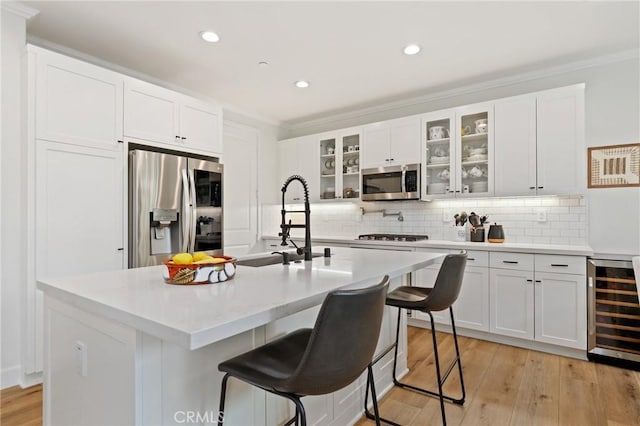 kitchen with ornamental molding, wine cooler, a sink, backsplash, and stainless steel appliances