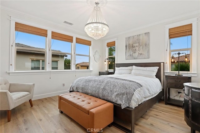 bedroom featuring crown molding, visible vents, light wood finished floors, and a chandelier