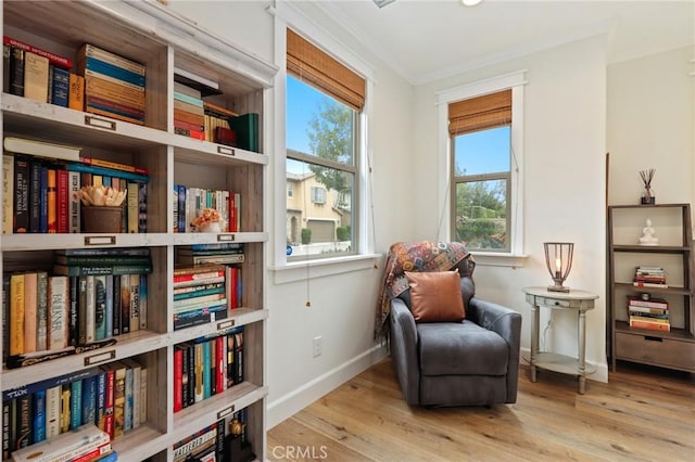 living area featuring crown molding, baseboards, and wood finished floors
