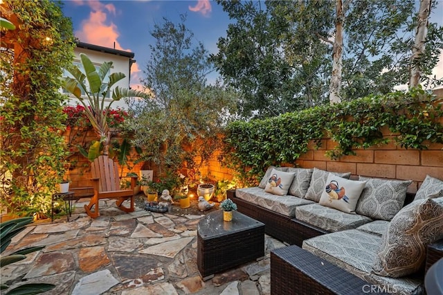 patio terrace at dusk featuring an outdoor living space and a fenced backyard