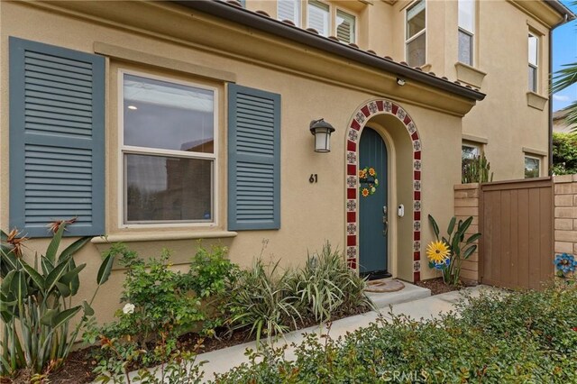 property entrance featuring fence and stucco siding