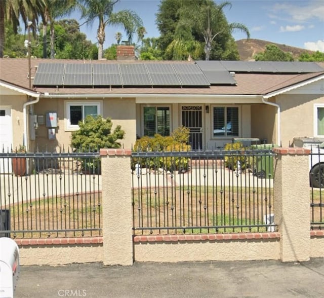 exterior space featuring a fenced front yard, stucco siding, a chimney, and solar panels