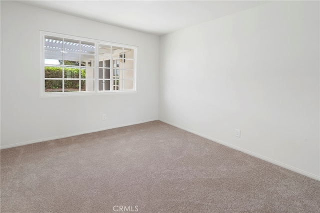 carpeted spare room featuring baseboards