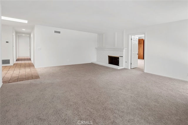 unfurnished living room featuring light colored carpet, baseboards, visible vents, and a fireplace