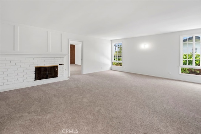unfurnished living room featuring light colored carpet, baseboards, and a brick fireplace