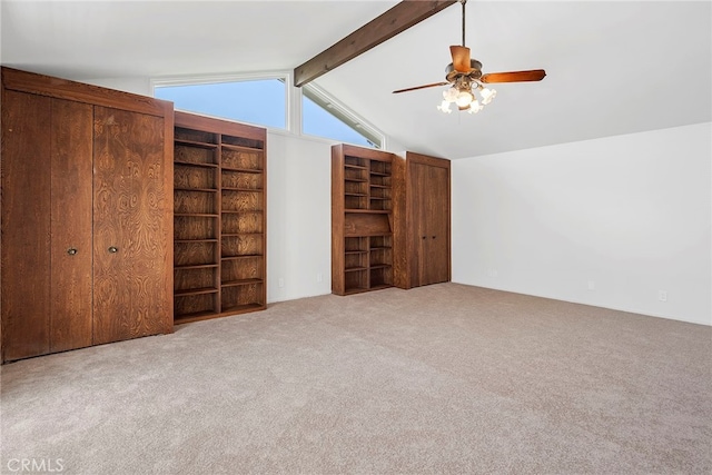 interior space featuring a ceiling fan, vaulted ceiling with beams, and carpet
