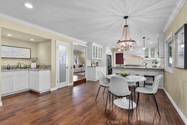 dining space with crown molding, baseboards, dark wood finished floors, and a chandelier