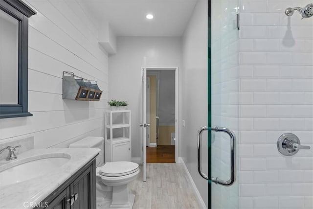 full bathroom with a shower stall, wood finished floors, vanity, toilet, and recessed lighting