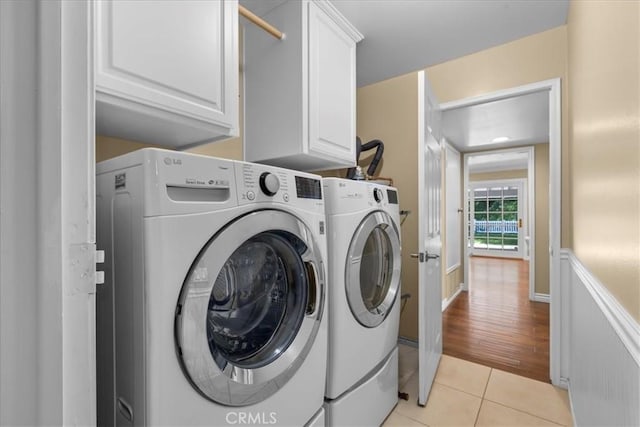 laundry area with cabinet space, light tile patterned flooring, and washer and clothes dryer