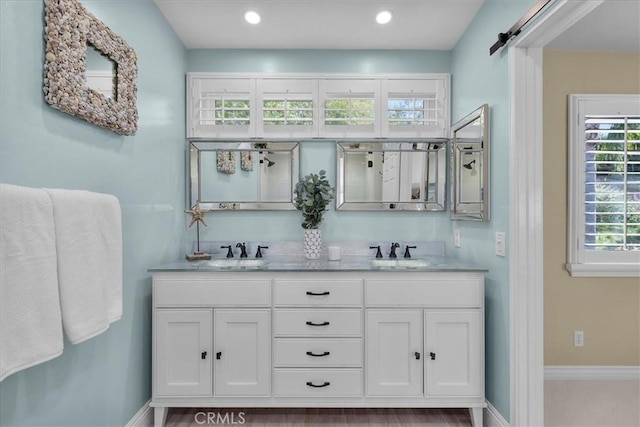 full bathroom featuring double vanity, baseboards, recessed lighting, and a sink