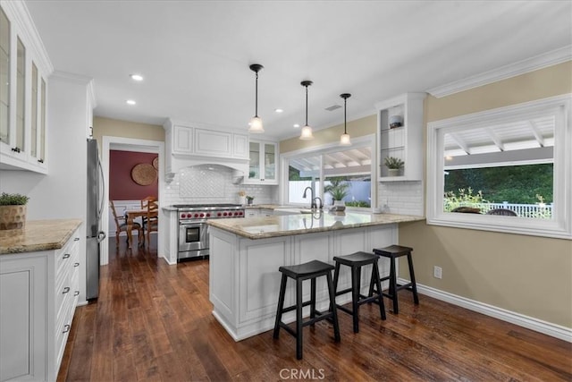 kitchen featuring tasteful backsplash, stainless steel appliances, a peninsula, and white cabinets