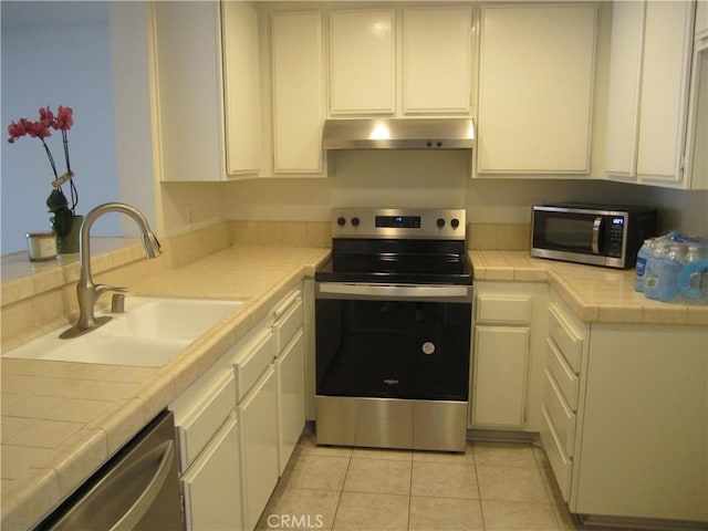 2321 S Magnolia Ave Unit 6A, Ontario, CA 91762 - kitchen with tile countertops, white cabinetry, under cabinet range hood, a sink, and stainless steel appliances