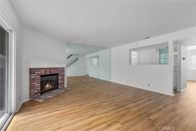 unfurnished living room featuring baseboards, a fireplace, wood finished floors, and visible vents