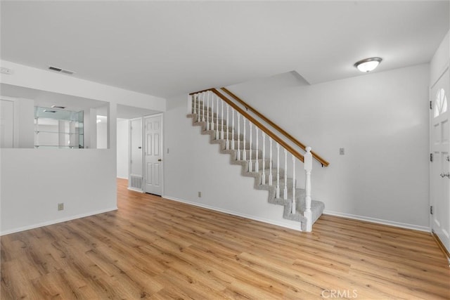 foyer with stairs, baseboards, visible vents, and wood finished floors