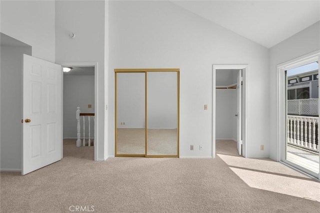 unfurnished bedroom featuring two closets, baseboards, high vaulted ceiling, access to outside, and carpet flooring