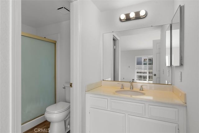 bathroom with visible vents, a shower stall, wood finished floors, vanity, and toilet