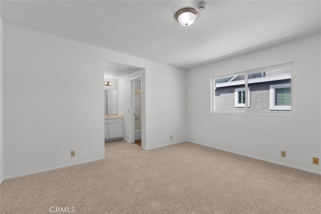 unfurnished bedroom with baseboards, light carpet, and connected bathroom