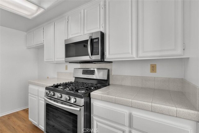 kitchen featuring appliances with stainless steel finishes, light wood finished floors, and white cabinetry
