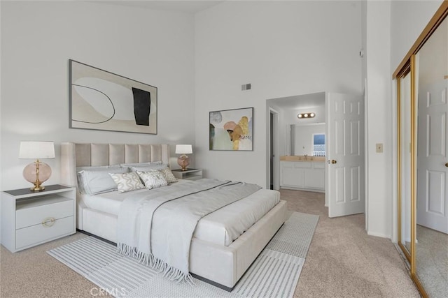 carpeted bedroom with baseboards, ensuite bath, and a high ceiling