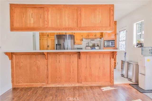 kitchen with light countertops, appliances with stainless steel finishes, tasteful backsplash, and light wood finished floors