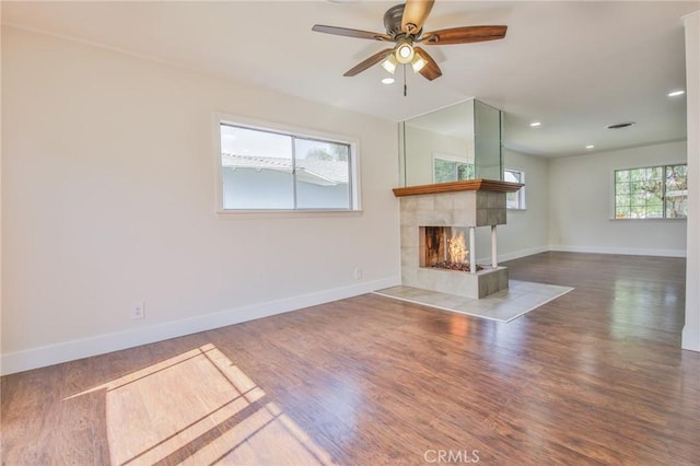 unfurnished living room with a ceiling fan, a fireplace, wood finished floors, baseboards, and recessed lighting
