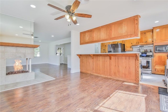 kitchen with appliances with stainless steel finishes, ceiling fan, a breakfast bar area, and recessed lighting
