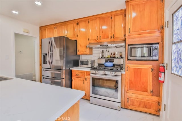 kitchen featuring under cabinet range hood, light countertops, marble finish floor, stainless steel appliances, and recessed lighting