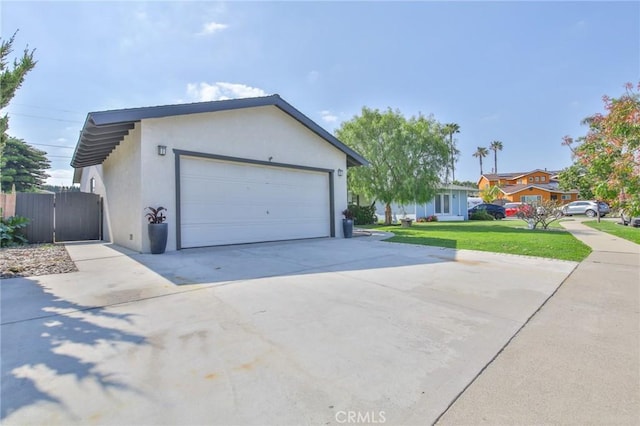 exterior space with a gate, a garage, a front lawn, concrete driveway, and stucco siding