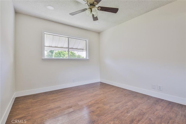 spare room featuring a textured ceiling, baseboards, and wood finished floors