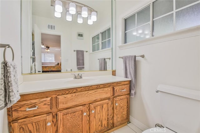 ensuite bathroom with connected bathroom, ceiling fan, vanity, toilet, and visible vents