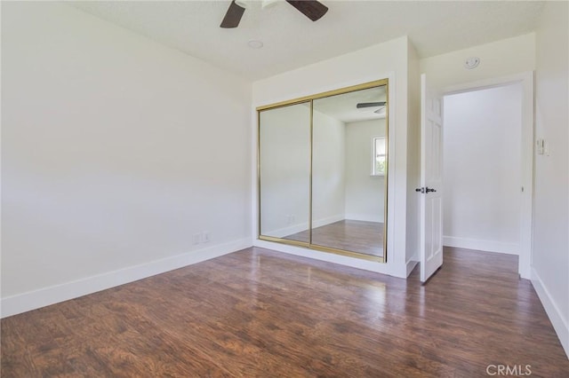 unfurnished bedroom featuring baseboards, ceiling fan, a closet, and wood finished floors