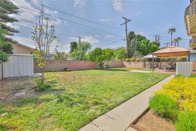 view of yard with a gazebo, a fenced backyard, a patio area, and a storage unit