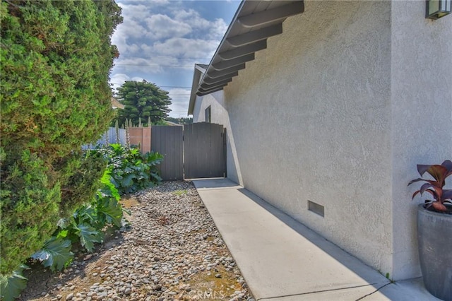 view of side of home with crawl space, a gate, and stucco siding