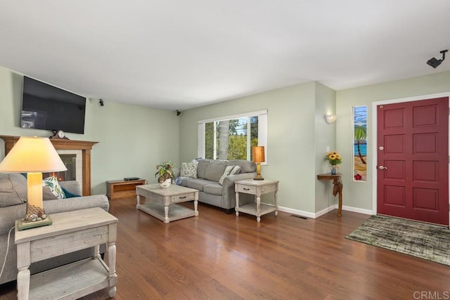 living room featuring visible vents, baseboards, a glass covered fireplace, and wood finished floors