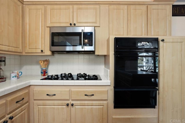 kitchen featuring backsplash, black appliances, and light brown cabinets