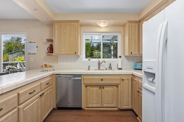 kitchen with light brown cabinetry, stainless steel dishwasher, white refrigerator with ice dispenser, a sink, and a wealth of natural light