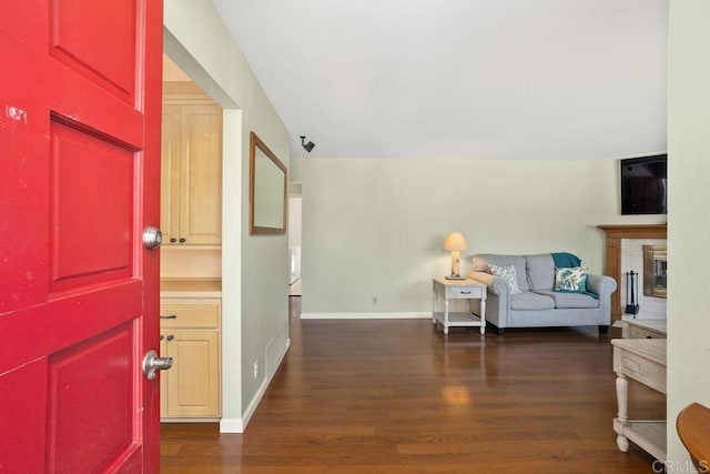 entrance foyer featuring a glass covered fireplace, baseboards, and wood finished floors