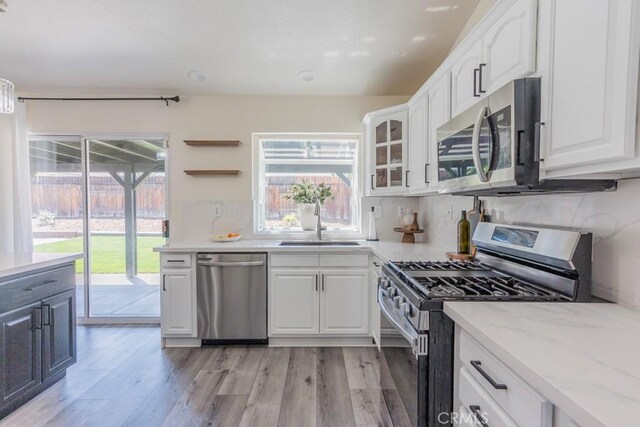 36711 Silverspur Ln, Palmdale, CA 93550 - kitchen featuring appliances with stainless steel finishes, light stone countertops, a sink, light wood-style floors, and white cabinetry