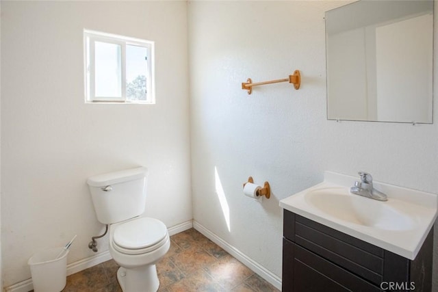half bath with toilet, baseboards, and vanity