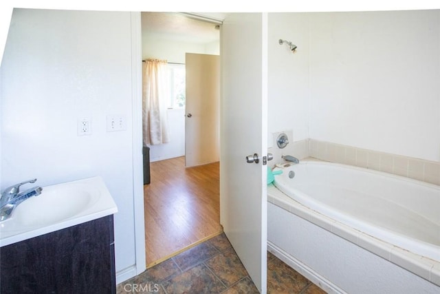 full bath featuring vanity, a washtub, and stone finish flooring