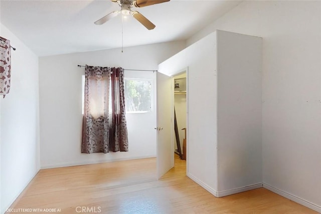 unfurnished bedroom with baseboards, ceiling fan, wood finished floors, and vaulted ceiling
