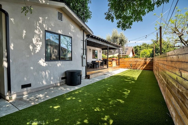view of yard featuring a pergola, a wooden deck, a fenced backyard, and a patio area
