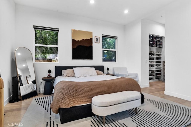 bedroom featuring baseboards, multiple windows, recessed lighting, and wood finished floors