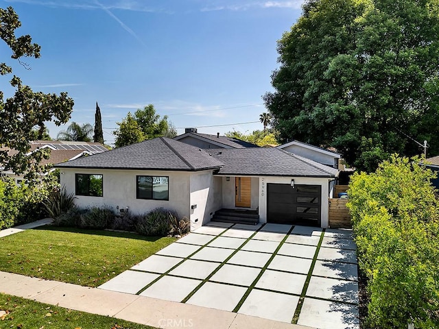 view of front facade with roof with shingles, a garage, a front lawn, concrete driveway, and stucco siding