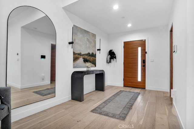 foyer entrance featuring arched walkways, baseboards, recessed lighting, and wood finished floors