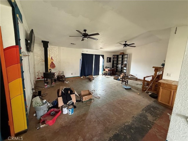 living area with a ceiling fan, visible vents, and a wood stove