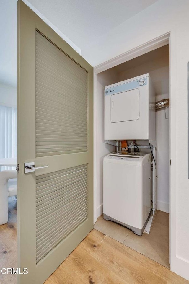 laundry room with baseboards, light wood-style flooring, stacked washer / dryer, and laundry area