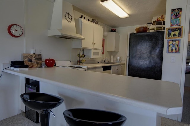 kitchen with a sink, freestanding refrigerator, a peninsula, custom range hood, and white electric stove