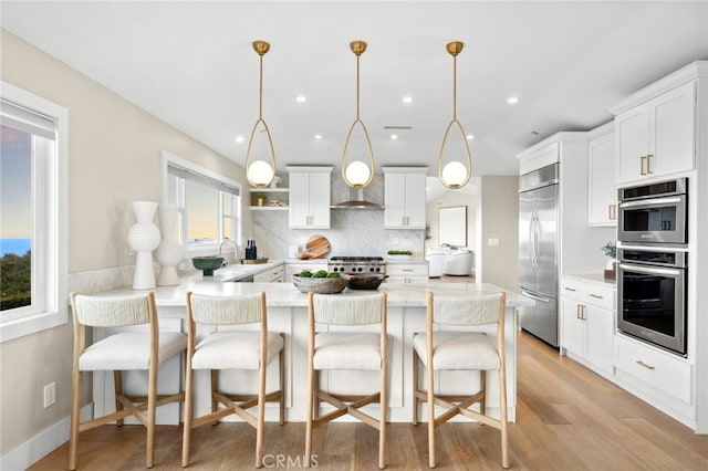kitchen featuring a sink, stainless steel appliances, a peninsula, decorative backsplash, and a kitchen bar