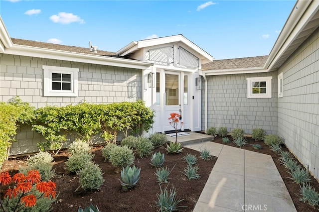 doorway to property with a shingled roof